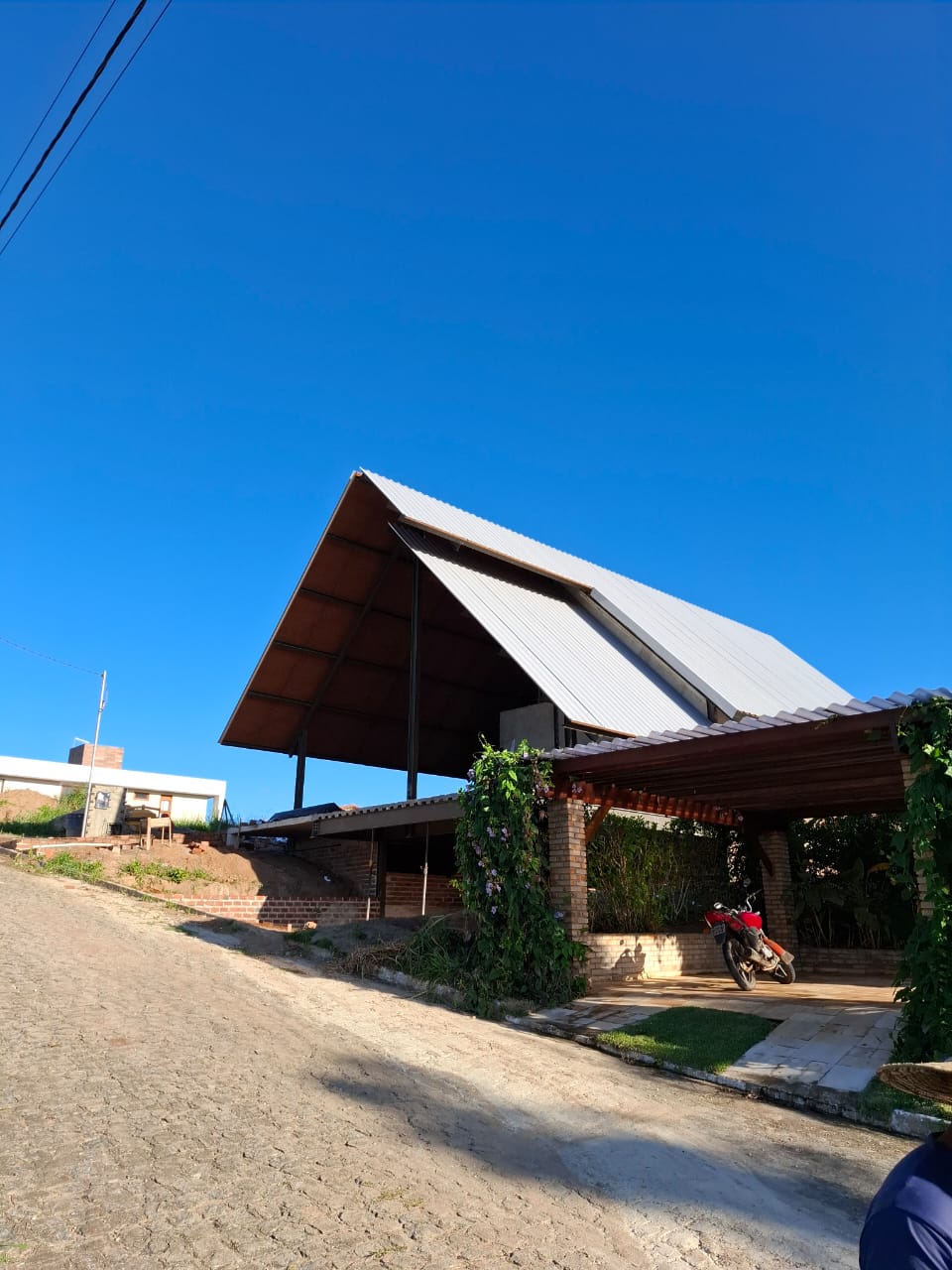 Chalé A-frame de alto padrão com grande telhado metálico de forte caimento e área coberta com pergolado, obra real